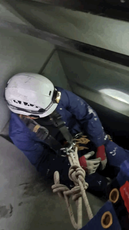 Rope Access Cladding Inspection In Confined Space Rope access technician in white helmet and harness inspecting inside a cladding cavity during a survey